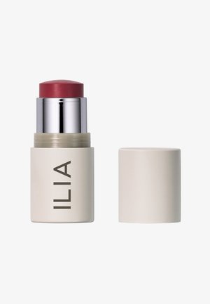 Ilia blush stick presenta una texture cremosa e morbida con una parte superiore rotonda di un rosa profondo e una base cilindrica in avorio opaco con il marchio scritto in un font pulito.