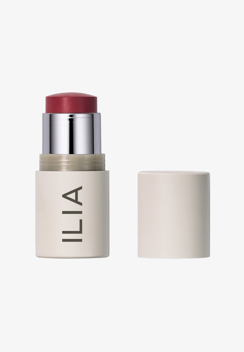 El blush stick de ILIA presenta una textura cremosa y suave con una parte superior redondeada de un rosa profundo y una base cilíndrica mate en color marfil, con la marca en una fuente limpia.