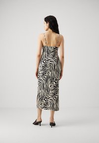Midi obleka z zebra vzorcem, tankimi naramnicami, prilegajočim telesom in ohlapnim krilom. Narejena iz lahkega blaga v črni in kremasti barvi.