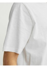 Hvid kortærmet t-shirt med rund hals, lavet af letvægtsstof, med en glat tekstur og minimal syning.