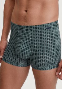 Strakke boxershorts in donkerblauw met een geometrisch teal-patroon. Gemaakt van een gladde stof met een elastische tailleband en zonder zichtbare naden.