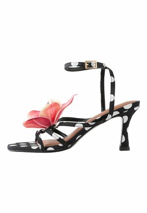 Fekete-fehér pöttyös magas sarkú szandál boka pánttal és nagy rózsaszín virág díszítéssel az elülső pántokon.