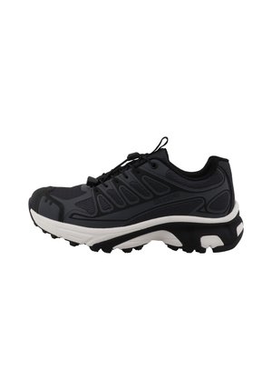 Zapatilla deportiva negra y gris con suela blanca, parte superior de malla y sistema de cordones seguro, diseñada para correr al aire libre o en senderos.
