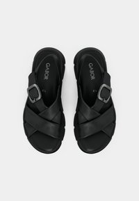 Black sandals with a cross strap design, made of smooth material. Features a silver buckle accent and sturdy rubber sole.