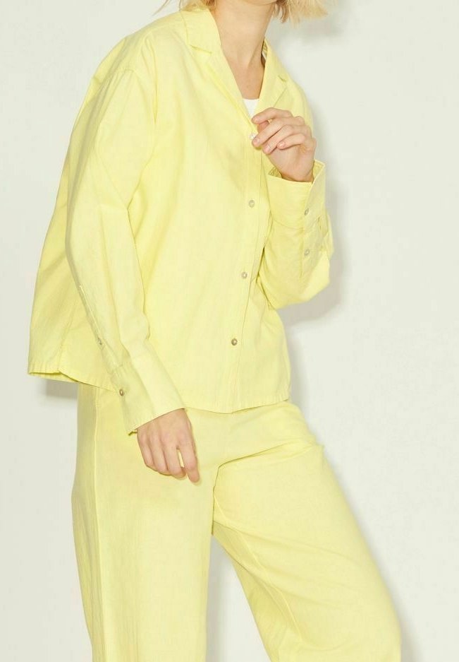 Camisa amarilla de botones y pantalones a juego en una tela suave y ligera. La camisa presenta un corte holgado con cuello y mangas largas.