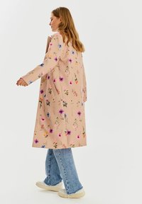 Dlhý, ružový květovaný kabát s rôznymi farebnými kvetmi. Má rovný strih a bočné vrecká, kombinovaný so svetlomodrými širokými džínsami.