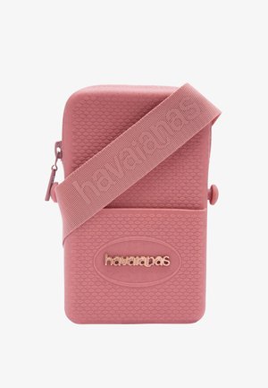 Bolso bandolera rosa texturizado con el logo en relieve "havaianas" y una correa ancha a juego que también presenta la marca "havaianas".