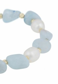 Armband med glaspärlor i oregelbundet ljusblått havsglas och vita pärlor, åtskilda av små gyllene distanser. Slät yta och organisk form.