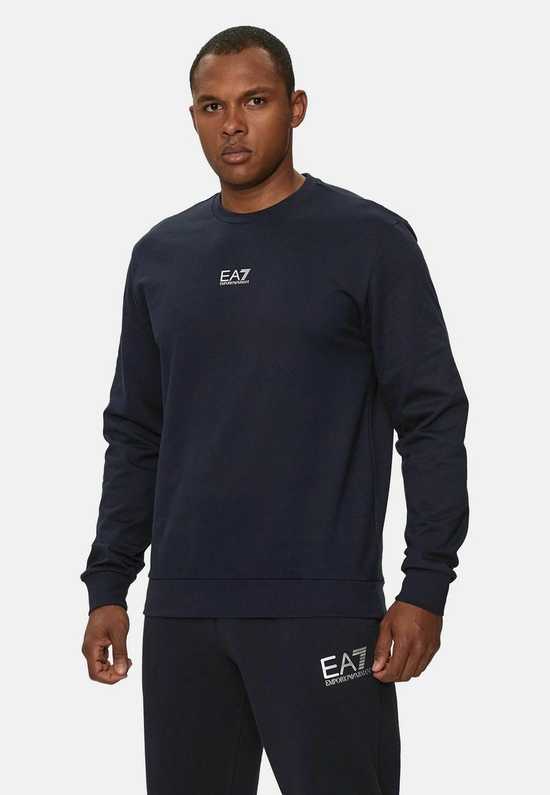 Felpa blu navy con maniche lunghe, collo tondo e logo EA7 ricamato sul petto. Realizzata in un tessuto morbido e strutturato.