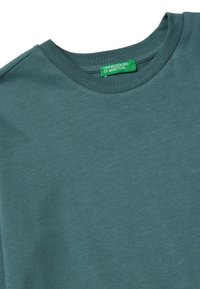 T-shirt verde acqua con scollo rotondo in tessuto misto cotone, caratterizzato da una texture liscia e un'etichetta verde con la scritta "UNION COLORS OF BENETTON".