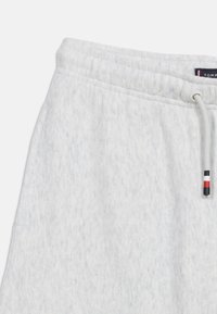 Ανοιχτό γκρι φόρμα με ελαστική ζώνη μέσης και κορδόνι με μαύρες, λευκές και κόκκινες λεπτομέρε ιες στις άκρες.