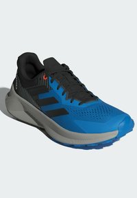 Blå träningsskor med svarta accenter, ett andningsbart meshöverdel, dämpad sula och ett framträdande design med tre ränder. Släta och texturerade ytor.