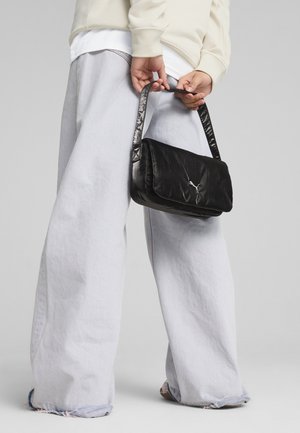 Bolso de hombro de cuero negro con una textura suave, forma rectangular y una correa acolchada y brillante. Presenta un logo sutil en la parte frontal.