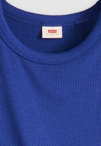T-shirt blu a coste con scollo rotondo, etichetta con la scritta "Levi's" e taglia "S". La texture appare morbida e elastica, adatta per l'abbigliamento casual.