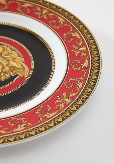 Dekoracyjny talerz z białym środkiem z czarnym kołem, czerwonym obramowaniem i misternymi złotymi kwiatowymi wzorami, prezentujący szczegółowe detale i kontrast.