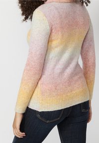 Knit sweater with a blend of pastel colors transitioning from pink to yellow, featuring a high collar and ribbed hem, worn with dark jeans.