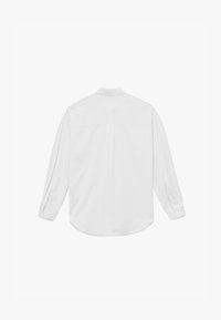 Camisa blanca de manga larga hecha de una tela suave. Presenta un cuello abotonado, un yugo trasero único y un dobladillo redondeado. Botones en los puños.