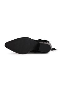 Μαύρη σόλα παπουτσιού με μυτερή μύτη, υφασμένη λαβή, εμφανές τακούνι και διακοσμητικές φούντες που εκτείνονται από το πάνω μέρος.