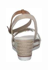 Sandales compensées beige avec un talon en paille texturée et un semelle intérieure blanche. Elles disposent d'une sangle à la cheville à l'arrière avec un accent en cuir tan et une tige en tissu.