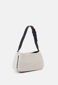 Witte fleece tas met een zwarte leren riem. Heeft een afgeronde vorm en een structuur. Voorzien van goudkleurige hardware-accenten.
