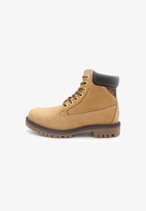 Stivale alla caviglia in pelle marrone chiaro con collo imbottito marrone, suola robusta, occhielli in metallo e logo Jeep sul lato vicino al tallone.