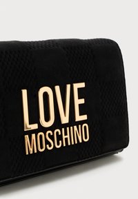 Borsa nera con texture, dotata di un grande logo dorato lucido "LOVE MOSCHINO" sul frontale.