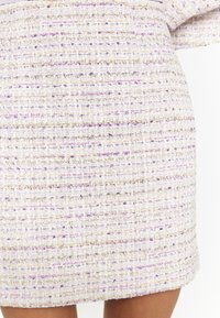 Wovenes Kleid in hellem Lavendel mit strukturiertem Stoff. Mit lila und goldenen Fadenakzenten sowie einem strukturierten, geraden Schnitt.