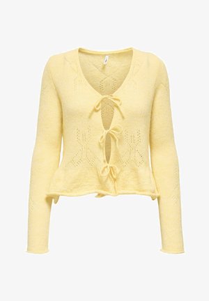 Gele gebreide cardigan met een V-hals, sluiting met strik aan de voorkant en lange mouwen. Heeft kanten patronen en een peplum zoom. Zachte textuur.