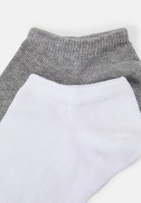 Calcetines de algodón grises y blancos con puños acanalados, que exhiben una textura suave y colores contrastantes. Diseño clásico sin patrones ni acentos.