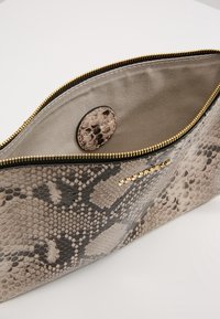Clutch bag con stampa serpente nei toni di nero e grigio, zip dorata e un interno beige chiaro. Presenta una tasca tonda interna.