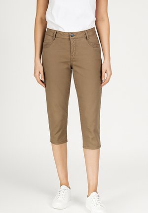 Brown capri pants made of cotton blend, featuring a zip fly, front pockets, and cuffed hems. Paired with white sneakers and a white shirt.