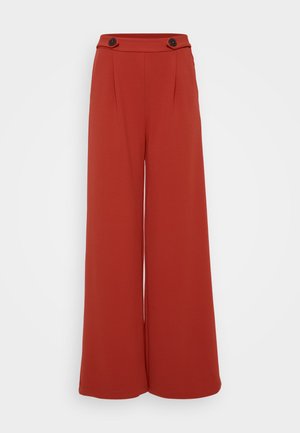 Pantalons larges en tissu rouge-orangé profond. Présentent deux plis à l'avant et deux boutons à la taille. Texture lisse, design décontracté.