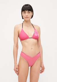 Ružičasti bikini set s trokutastim topom s cvjetnim uzorkom, crnim obrubom i visokim donjim dijelom s izrezom u obliku slova V. Glatka tekstura.