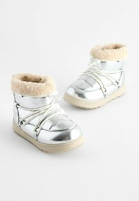 Silverfärgade metallicstövlar med fuskpälskrage, textilöverdel, förstärkt tå och gummisula. Snören och detaljer i vitt.