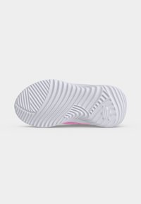 Semelle blanche de basket avec des rainures et crêtes ondulées texturées pour l'adhérence, montrant une partie supérieure rose partielle.