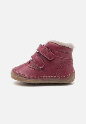 Botte en cuir bordeaux pour enfant, avec une doublure en fausse fourrure beige, deux bandes velcro et une semelle en caoutchouc tan.