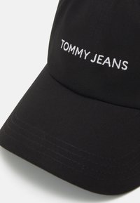 Čierny baseballový šiltovka vyrobený z bavlny s pevnou konštrukciou. Na prednej strane sa nachádza biele vyšívané logo "TOMMY JEANS".