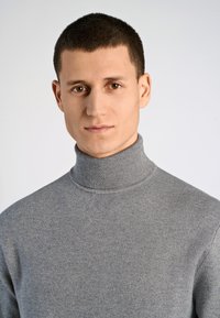 Grauer Rollkragenpullover aus glattem Stoff, mit hohem Kragen und gerippter Textur, in taillierter Passform.