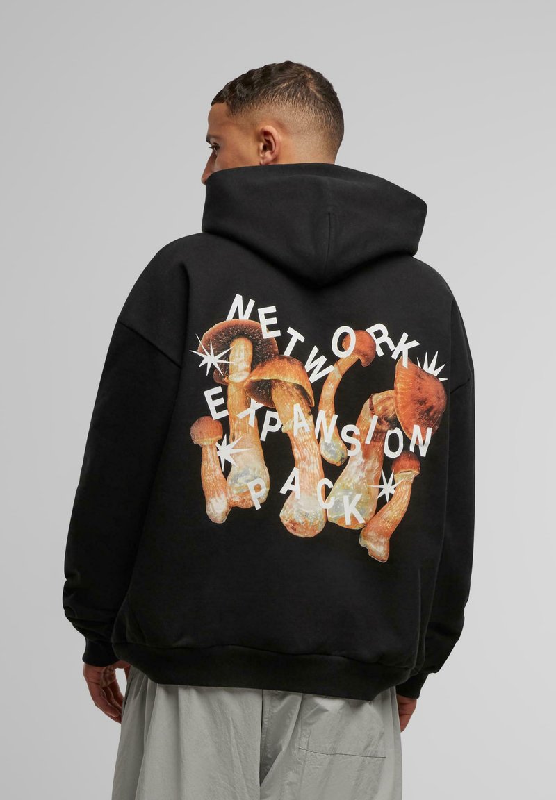 Sweatshirt à capuche noir arborant un grand graphique de champignons et un texte blanc indiquant "PACK D'EXPANSION DE RÉSEAU" au dos. Coupe décontractée.