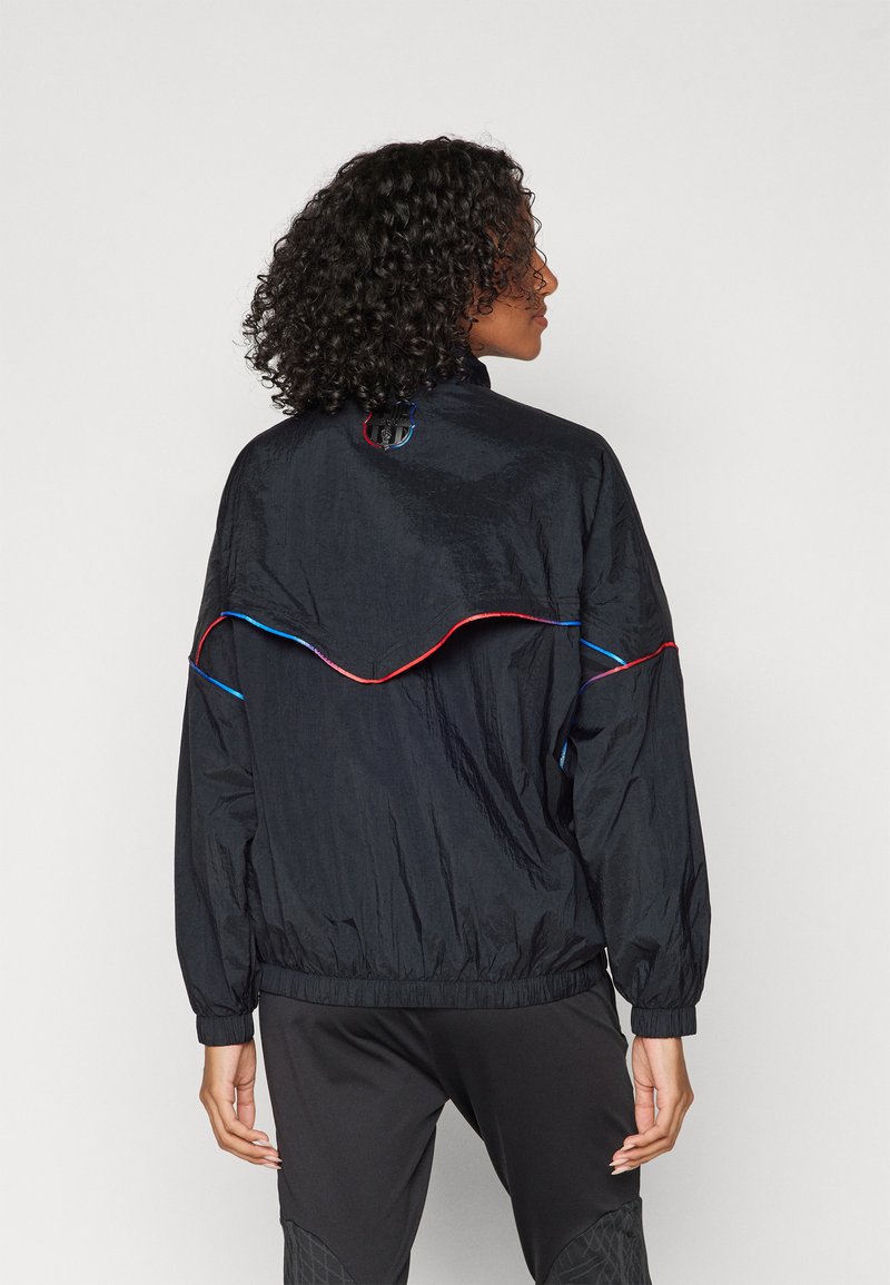 Schwarze leichte Jacke mit hohem Kragen, roten und blauen Akzenten, strukturiertem Stoff und einem geschwungenen Nahtdesign auf der Rückseite.