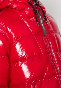 Chaqueta acolchada roja y brillante con capucha, que presenta un acabado acolchado, un cierre frontal de cremallera y una etiqueta de marca con la inscripción "PINKO."
