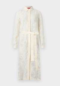 Μπλούζα-φόρεμα με μακριά μανίκια από εκρού δαντέλα, με γιακά, κουμπιά μπροστά και ζώνη από το ίδιο ύφασμα δεμένη στη μέση.