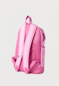 Ροζ σακίδιο πλάτης με μαξιλαρωμένη πλέκτη πλάτης, ρυθμιζόμενους ιμάντες ώμου με μικρά λευκά λογότυπα ελαφιών και λαβή στο πάνω μέρος, πάνω σε απλό φόντο.