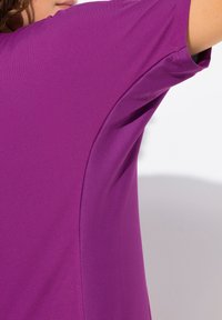 Paarse sportshirt met een gladde stof en een gestructureerd gaaspaneel aan de zijkant, korte mouwen en een ontspannen pasvorm.