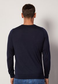 Navy blue sweater made of soft material, featuring long sleeves and a crew neck design. Minimalist style with no visible patterns or accents.