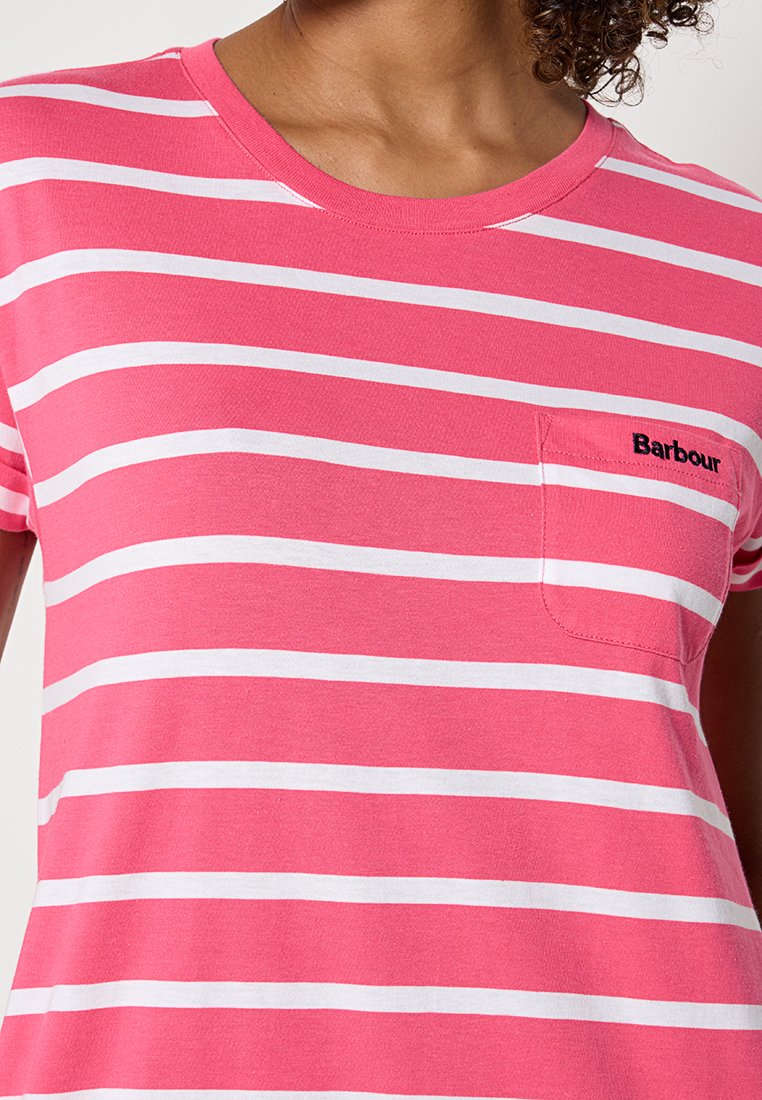 Zbliżenie na różowo-białą koszulkę w paski z kieszonką na piersi, na której znajduje się czarny haft z napisem "Barbour".