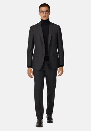 Maßgeschneiderter, dunkelgrauer Anzug mit einem Zweiknopf-Blazer und passender Hose, getragen über einem schwarzen Rollkragenpullover. Glattes Material, elegantes Design.