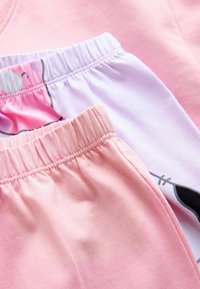 Light pink cotton sweatpants with elastic waistbands. Includes a pair with a white waistband featuring a cartoon print, showcasing playful design.