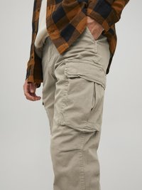 Beige cargo pants made from soft fabric, featuring side pockets, straight cut, and visible stitching details.