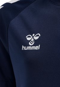 Granatowa koszulka sportowa wykonana z gładkiego poliestru z subtelnym połyskiem. Posiada białe logo "hummel" oraz charakterystyczny wzór pszczoły.